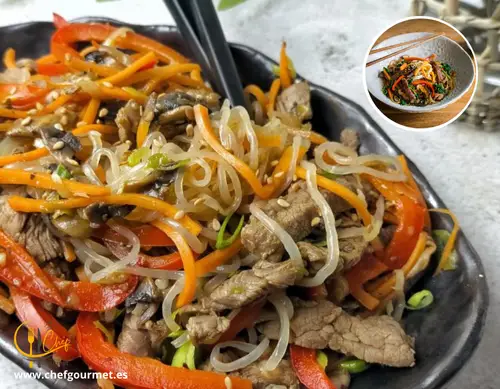 Plato coreano Japchae con fideos de boniato, zanahoria, espinacas, champiñones y ternera, servido en un bol tradicional