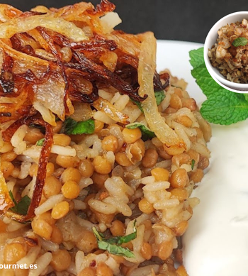 Plato de mujaddara libanés con arroz y lentejas mezclados, cubiertos con cebolla caramelizada crujiente, servido en bol rústico