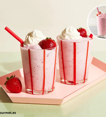 Milkshake de fresa en un vaso con fresas frescas alrededor