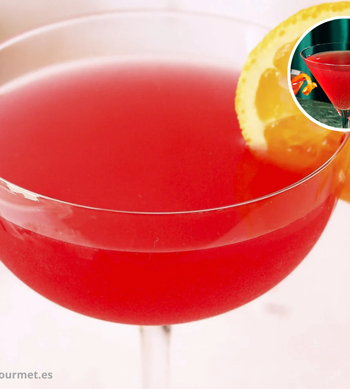 Cóctel Cosmopolitan en copa tipo Martini, de color rosa, hecho con vodka, arándano, triple sec y lima, decorado con rodaja de lima