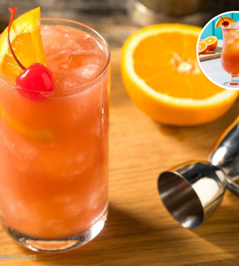 Cóctel Sex on the Beach en vaso alto con hielo, mezcla de vodka, licor de melocotón, zumo de naranja y arándano, decorado con naranja y cereza