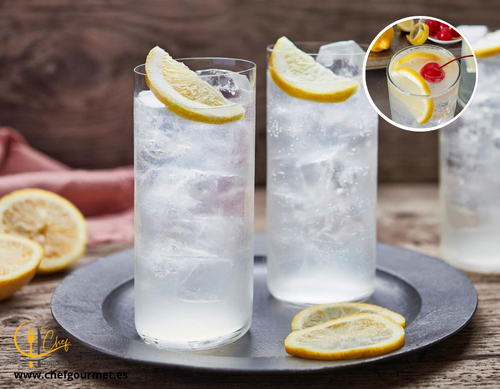 Cóctel Tom Collins con ginebra, limón, soda y hielo en vaso alto decorado con rodaja de limón y cereza.