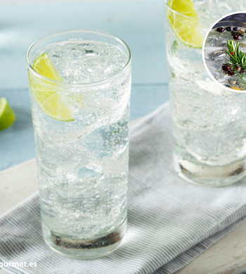 Cóctel Gin Tonic en copa balón con hielo, ginebra, tónica, rodaja de lima y bayas de enebro