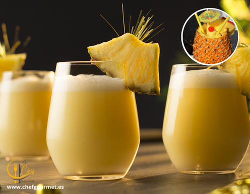 Cóctel Piña Colada en vaso alto con hielo, preparado con ron, crema de coco y piña, decorado con fruta tropical y sombrilla