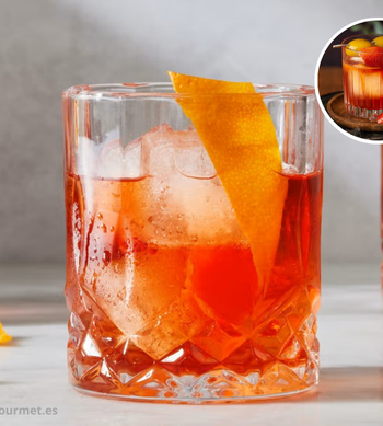 Cóctel Negroni servido en vaso bajo con hielo, mezcla de ginebra, vermut rojo y Campari, decorado con una rodaja de naranja